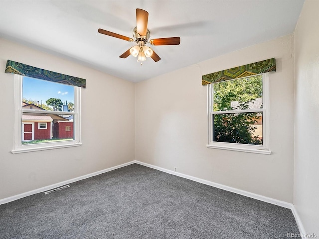 carpeted empty room with baseboards, a ceiling fan, and visible vents