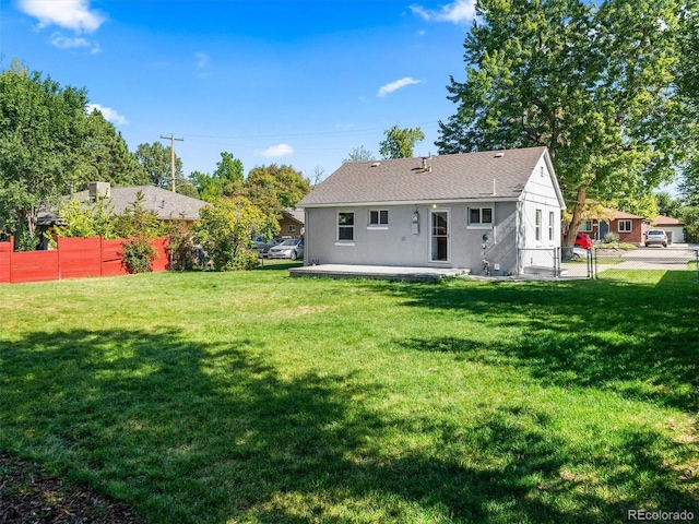 back of property with a shingled roof, a patio area, fence, and a lawn