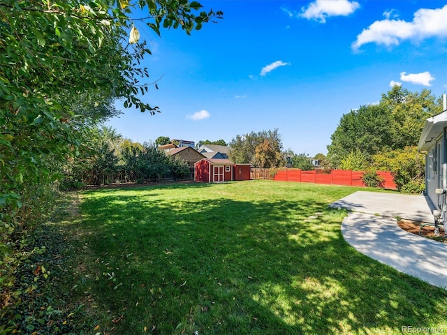 view of yard featuring an outdoor structure, a patio area, a fenced backyard, and a shed