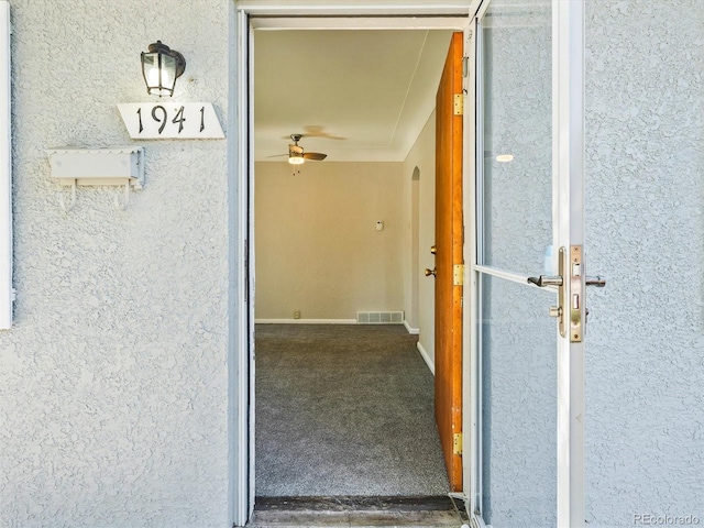 entrance to property featuring stucco siding and visible vents
