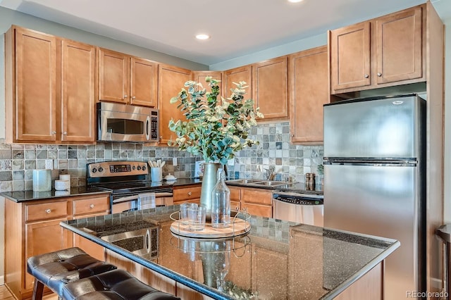 kitchen with backsplash, appliances with stainless steel finishes, a breakfast bar, and dark stone countertops