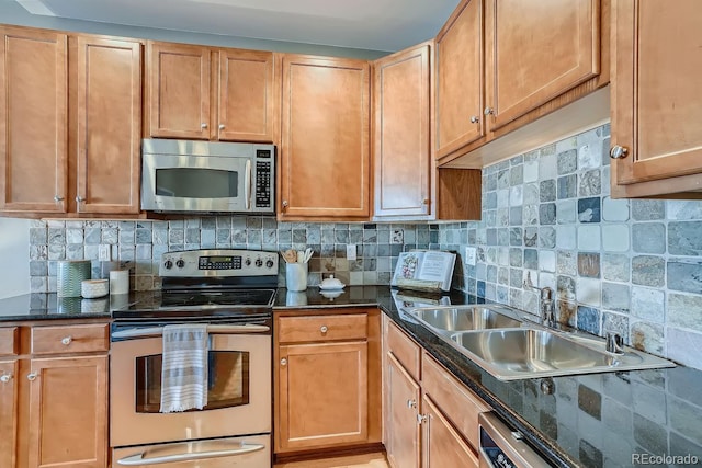 kitchen with dark stone countertops, sink, backsplash, and appliances with stainless steel finishes