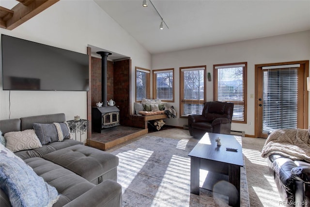 carpeted living room with a wood stove, track lighting, lofted ceiling, and a baseboard heating unit