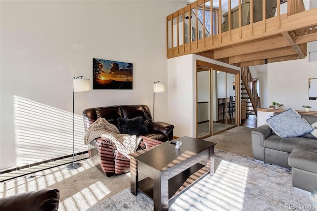 carpeted living room featuring beam ceiling and a high ceiling