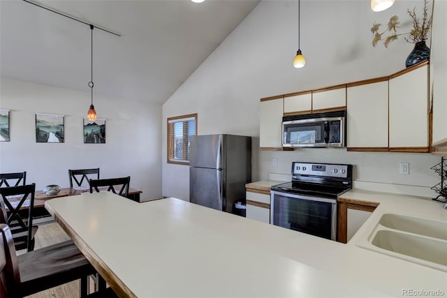 kitchen featuring pendant lighting, stainless steel appliances, white cabinetry, and a kitchen breakfast bar