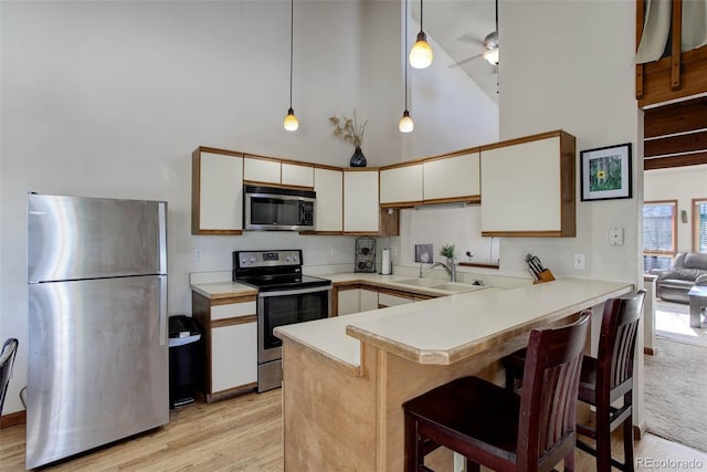 kitchen with kitchen peninsula, white cabinetry, stainless steel appliances, and decorative light fixtures