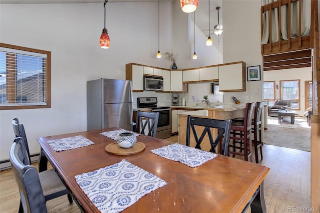 dining area with light hardwood / wood-style flooring, high vaulted ceiling, and sink