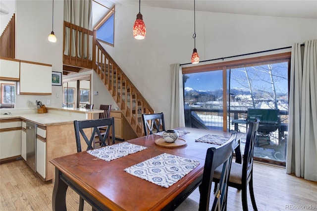 dining room with light wood-type flooring and high vaulted ceiling