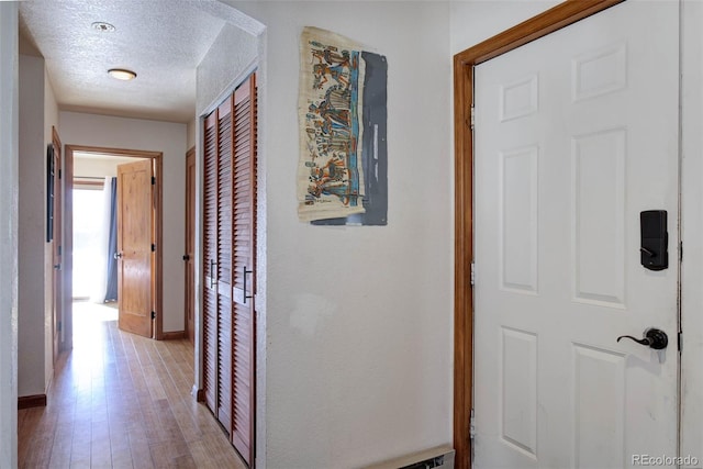 corridor with a textured ceiling and light wood-type flooring