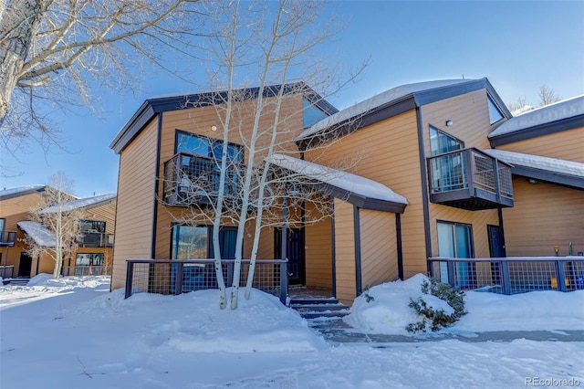 snow covered back of property with a balcony