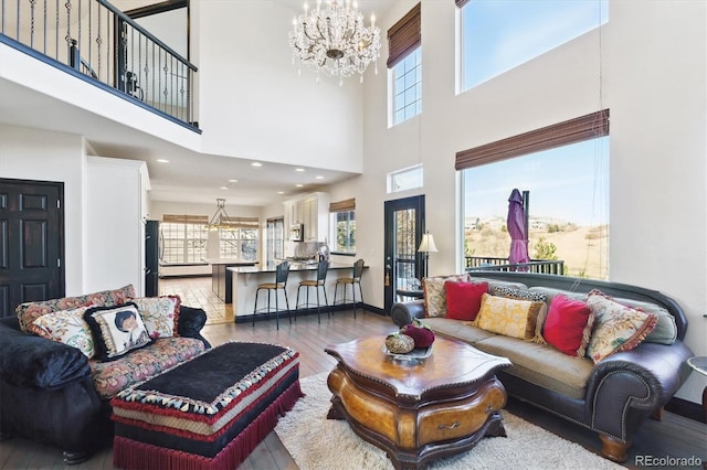 living room with a chandelier, a high ceiling, hardwood / wood-style flooring, and plenty of natural light