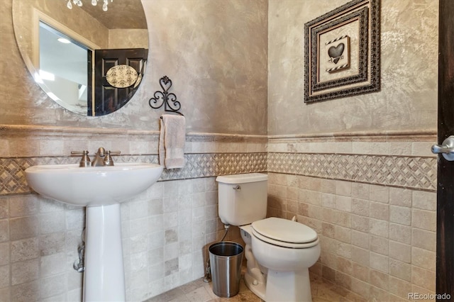 bathroom featuring tile patterned flooring, tile walls, and toilet