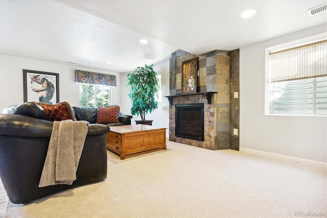 carpeted living room featuring a stone fireplace