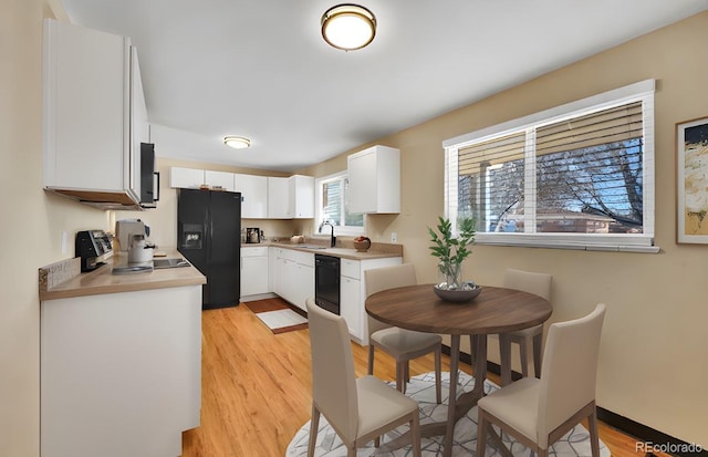 kitchen with white cabinetry, sink, light hardwood / wood-style floors, and black appliances