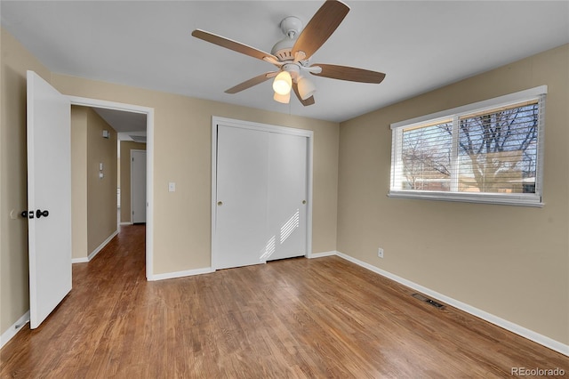 unfurnished bedroom featuring hardwood / wood-style flooring, ceiling fan, and a closet