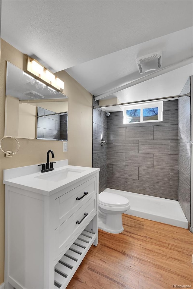 bathroom with vanity, wood-type flooring, toilet, and tiled shower