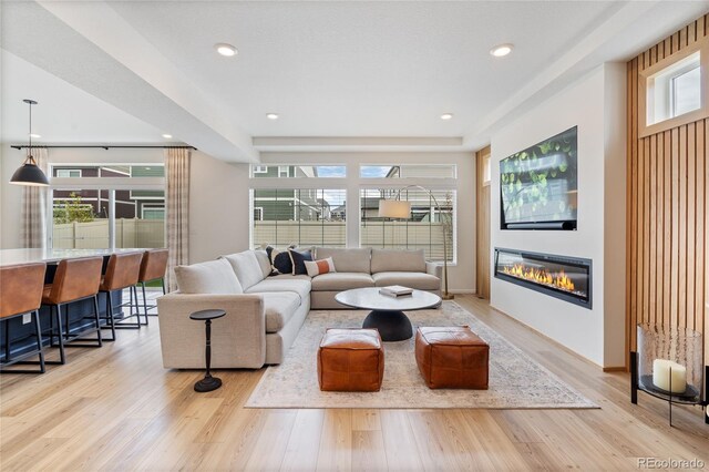 living area featuring a glass covered fireplace, light wood-style flooring, and recessed lighting