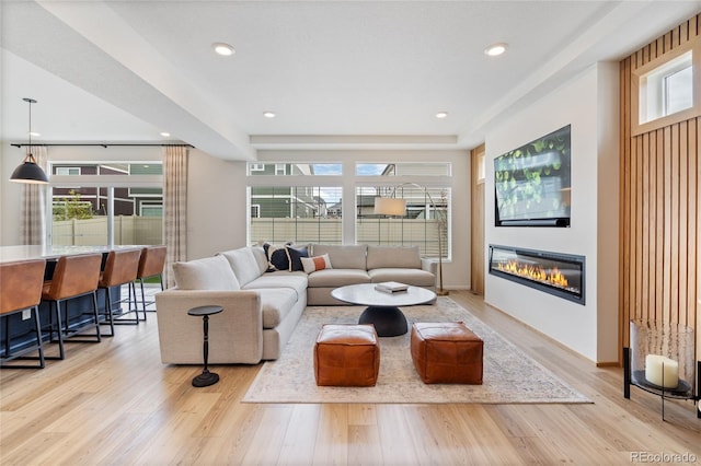 living area featuring a glass covered fireplace, light wood-style flooring, and recessed lighting