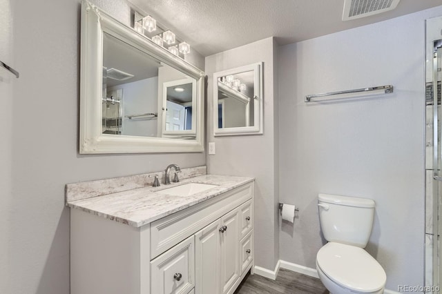 bathroom with hardwood / wood-style flooring, vanity, a textured ceiling, and toilet