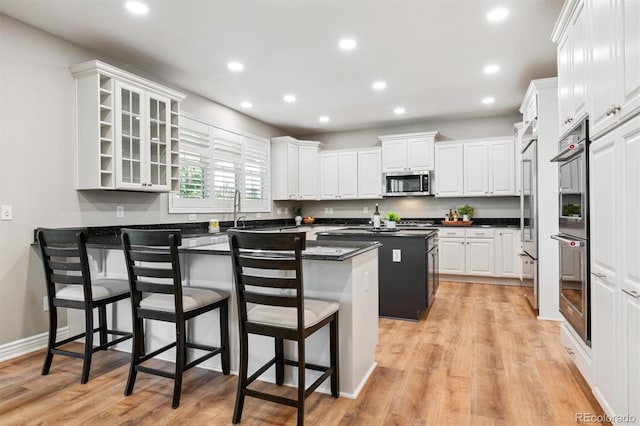 11911 E Lake Cir, Greenwood Village, CO 80111 - kitchen featuring appliances with stainless steel finishes, a kitchen breakfast bar, white cabinets, dark countertops, and a peninsula