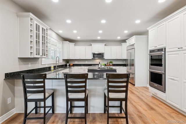 11911 E Lake Cir, Greenwood Village, CO 80111 - kitchen featuring stainless steel appliances, a peninsula, a kitchen breakfast bar, white cabinets, and recessed lighting