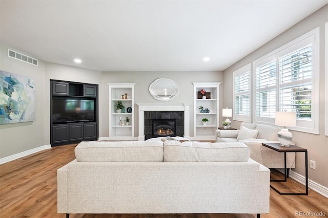 11911 E Lake Cir, Greenwood Village, CO 80111 - living room with light wood-type flooring, a tile fireplace, built in features, and recessed lighting