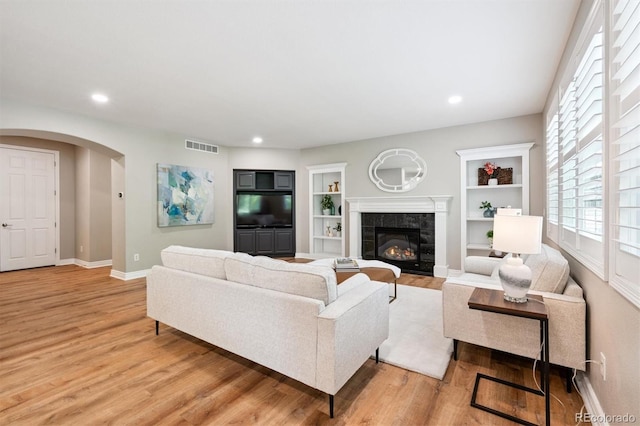 11911 E Lake Cir, Greenwood Village, CO 80111 - living room featuring light wood-style flooring, a fireplace, arched walkways, recessed lighting, and built in shelves