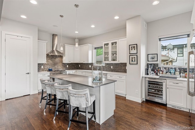 1373 S Garfield St, Denver, CO 80210 - kitchen featuring beverage cooler, wall chimney range hood, tasteful backsplash, white cabinets, and recessed lighting