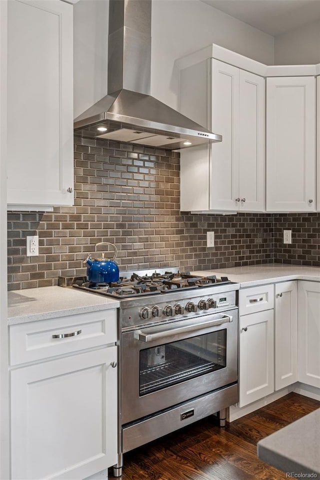 1373 S Garfield St, Denver, CO 80210 - kitchen featuring high end range, wall chimney exhaust hood, white cabinets, tasteful backsplash, and dark wood finished floors