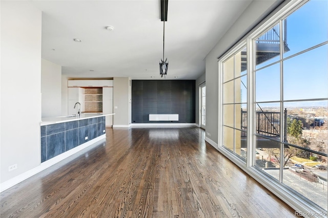 unfurnished dining area with dark wood finished floors and baseboards