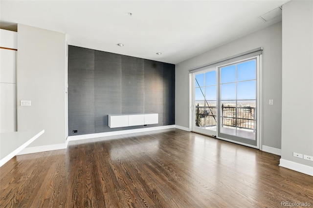 spare room featuring an accent wall, radiator heating unit, wood finished floors, and baseboards