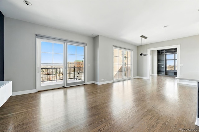 unfurnished living room with dark wood-style floors and baseboards