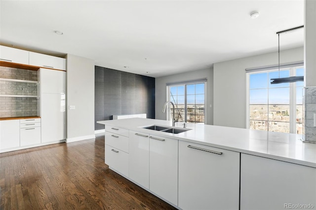 kitchen with modern cabinets, a sink, white cabinets, light countertops, and dark wood-style flooring