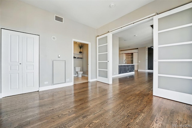 unfurnished living room with visible vents, baseboards, and wood finished floors