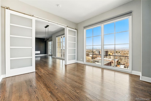 empty room featuring plenty of natural light, wood finished floors, baseboards, and french doors