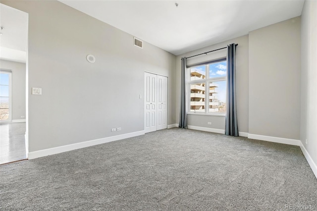 carpeted spare room featuring baseboards and visible vents