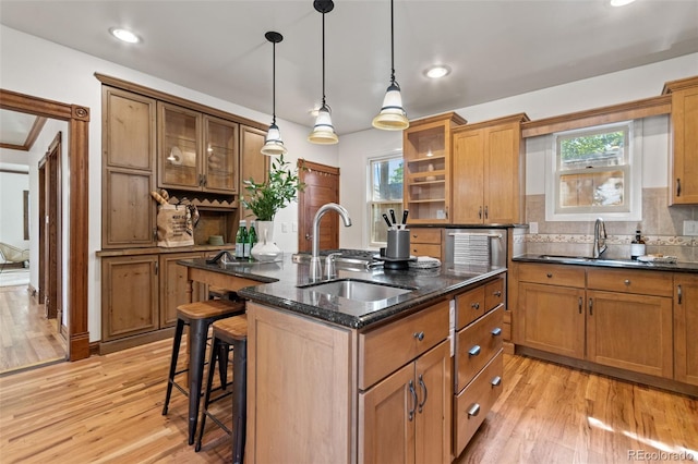 3039 W 22nd Ave, Denver, CO 80211 - kitchen featuring an island with sink, brown cabinetry, a breakfast bar, light wood-type flooring, and recessed lighting