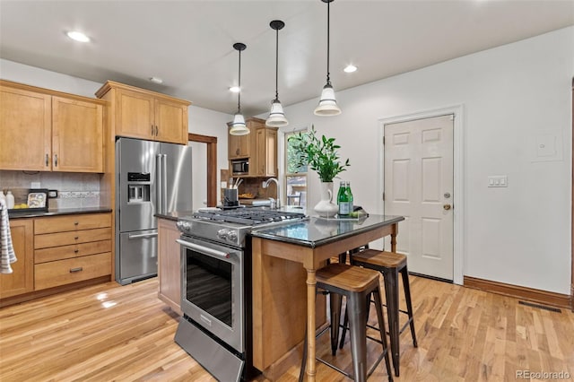 3039 W 22nd Ave, Denver, CO 80211 - kitchen featuring stainless steel appliances, dark countertops, a breakfast bar, light wood finished floors, and recessed lighting