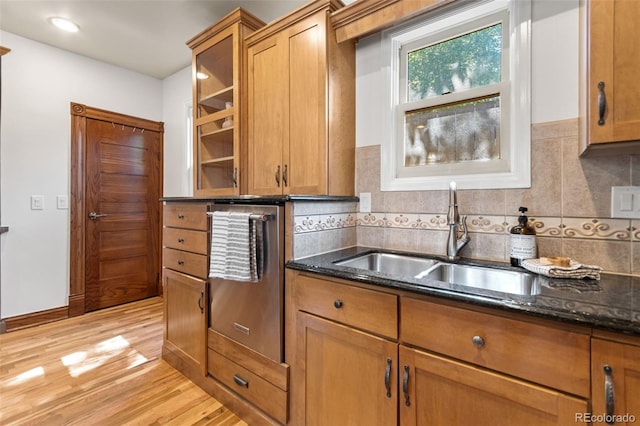 3039 W 22nd Ave, Denver, CO 80211 - kitchen featuring light wood-style floors, brown cabinetry, dark stone countertops, and backsplash