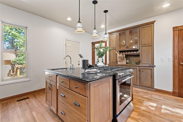 3039 W 22nd Ave, Denver, CO 80211 - kitchen with gas range, light wood-style floors, recessed lighting, a kitchen island with sink, and dark stone counters