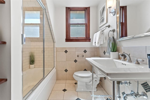 3039 W 22nd Ave, Denver, CO 80211 - bathroom featuring tile walls, tile patterned flooring, healthy amount of natural light, bath / shower combo with glass door, and wainscoting
