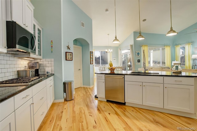 kitchen featuring white cabinetry, tasteful backsplash, hanging light fixtures, light hardwood / wood-style flooring, and stainless steel appliances