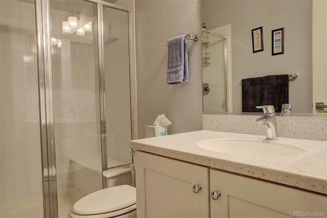 bathroom featuring a shower with door, vanity, and toilet