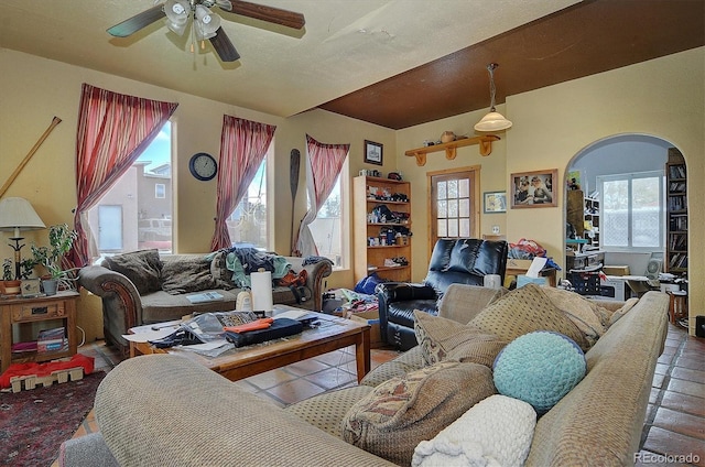 living room with a textured ceiling, ceiling fan, and plenty of natural light