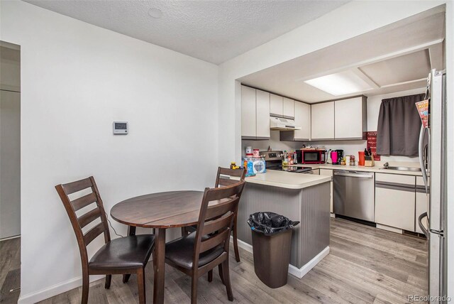 kitchen featuring a textured ceiling, light hardwood / wood-style flooring, stainless steel appliances, kitchen peninsula, and white cabinets