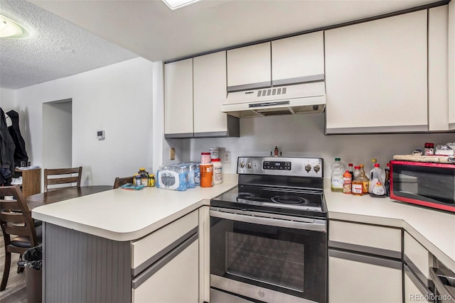 kitchen with hardwood / wood-style floors, electric range, kitchen peninsula, and a textured ceiling