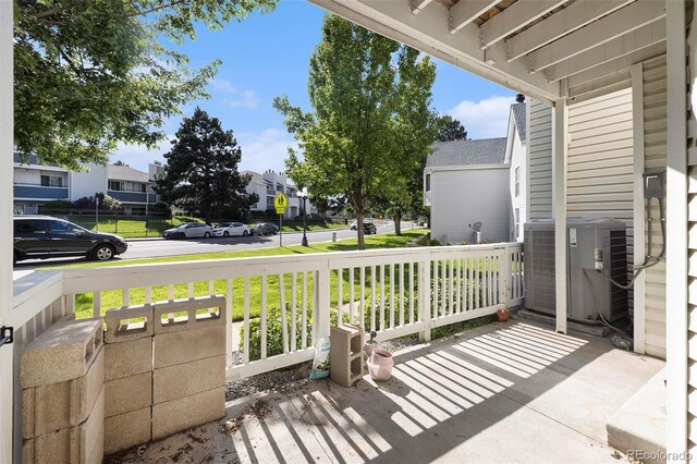 wooden deck featuring a lawn, central AC unit, and covered porch