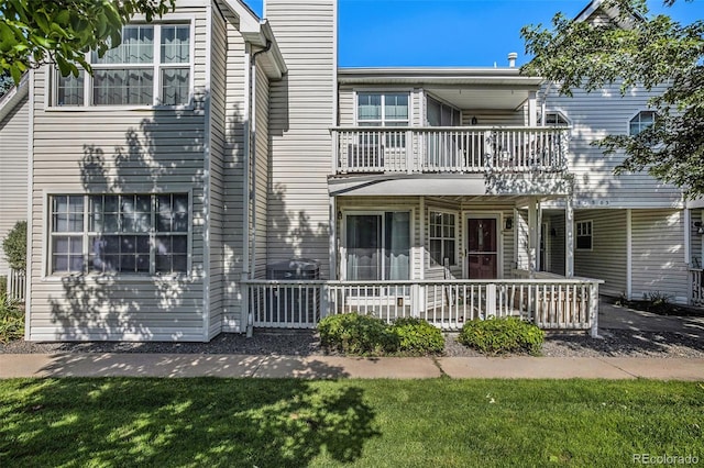 view of front of property with a porch, a balcony, and a front yard