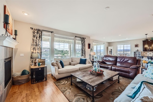 living room featuring light wood-type flooring, a tiled fireplace, and recessed lighting