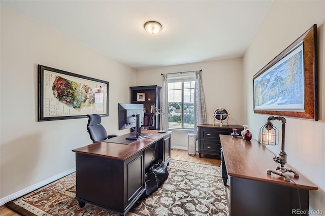 home office with light wood-style flooring and baseboards